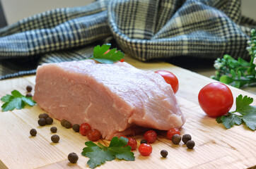 Raw pork meat on cutting board and vegetables and greens
