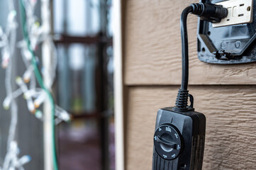 Outdoor timer and GCFI outlet with cover. Blurred christmas lights in background.