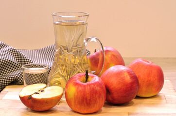 Apple cider vinegar in glass bottle and fresh apples on wooden background