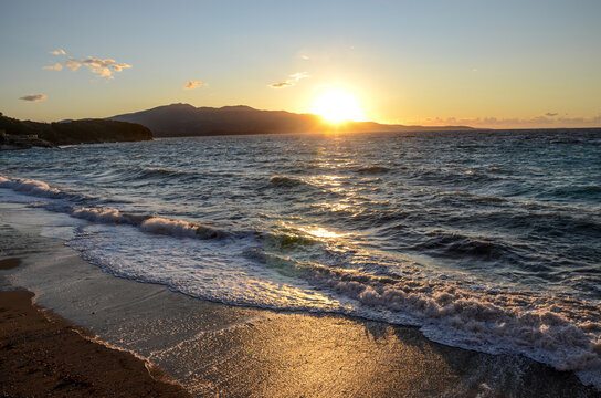 Sunset at the sea. Waves on water and sun is setting down in horizon. Summertime. 