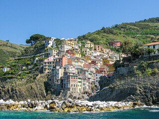 Cliffside houses stacked up the mountainside in different colors - Powered by Adobe