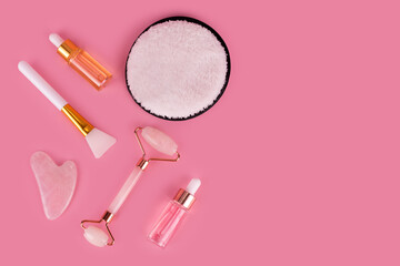 Naklejka premium Jade face roller and Gua sha stone for facial massage. Home skin care anti-aging tools, face serum bottle, massage roller. Natural organic essential oil, skincare beauty product. Flat lay, top view.