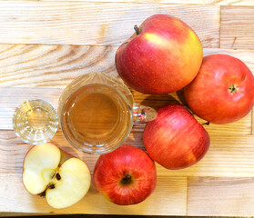 Apple cider vinegar in glass bottle and fresh apples on wooden background