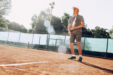 Middle-aged man playing tennis on outdoor tennis filed