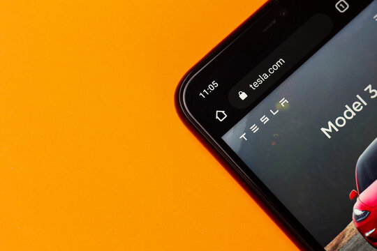 Balti, Moldova, March 3, 2020 corner of the smartphone on an orange background, with the official website of the American company Tesla tesla.com, illustrative editorial