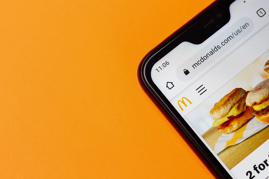 Balti, Moldova, March 3, 2020 corner of the smartphone on an orange background, with the official website of the American company McDonalds mcdonalds.com, illustrative editorial