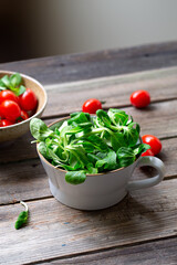 Corn salad in wide cup with cherry tomatoes , wooden table.
