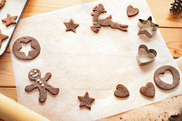 Homemade Christmas cookies on a wooden table with baking paper.