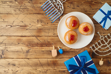 Jewish holiday Hanukkah background with traditional donuts, menorah and gift box