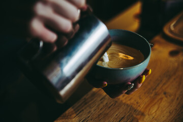 pouring milk into a cup of coffee. making latte, cafe. Barista is making coffee. Coffee in beautiful ceramic blue purple magenta color cup. Coffee shop.coffee in the morning.