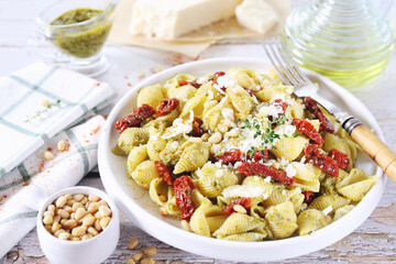 Conchiglie rigate pasta  with pesto sauce and sun dried tomatoes, grated parmesan cheese and pine nut