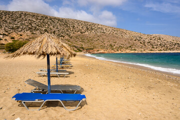 Sun beds and umbrellas at Agia Theodoti beach on Ios Island. A wonderful beach with the golden sand...