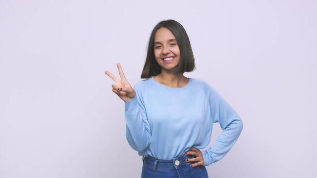 Young mixed race woman joyful and carefree showing a peace symbol with fingers