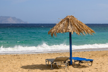 Sun beds and umbrella at Agia Theodoti beach on Ios Island. A wonderful beach with the golden sand...