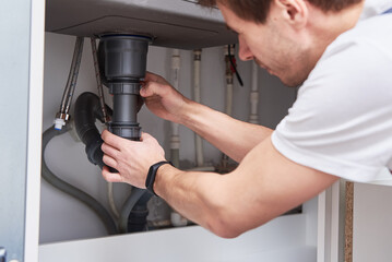 Fototapeta na wymiar Male plumber repair sink pipe in kitchen