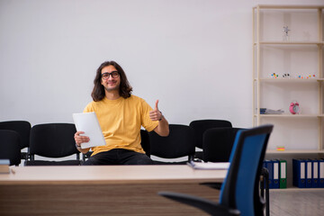 Young male student waiting for teacher in the classroom