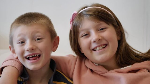 brother and sister are smiling and laughing together at home