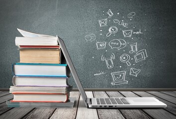 Stack of books with laptop on wooden table
