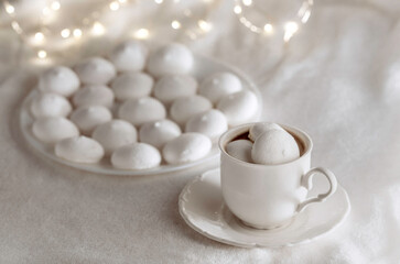 Obraz na płótnie Canvas White cup of coffee with meringues on soft blanket.