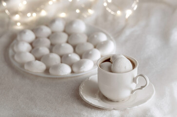 White cup of coffee with meringues on soft blanket.
