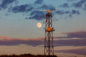 telecommunication antenna tower and moon at sunset time