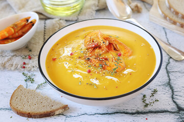 Pumpkin cream soup with fried shrimps, bread and olive oil