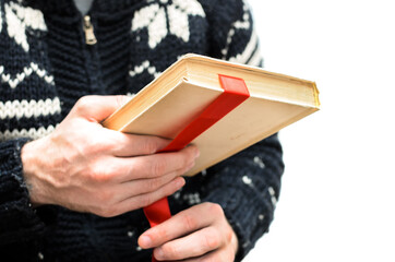 man holding an old book in his hands, with a ribbon between the pages