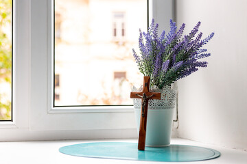Wooden cross and lavender bouquet by the window