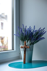 Cross on the windowsill and a bouquet of lavender