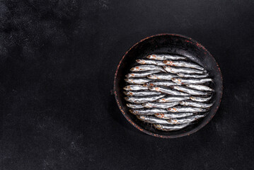 Several fish salted anchovies on a dark concrete table