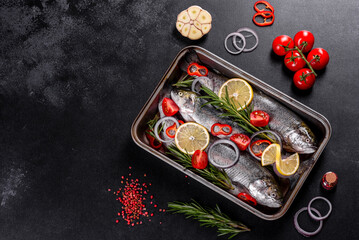Raw trout lie on a black stone chopping board on a dark concrete table