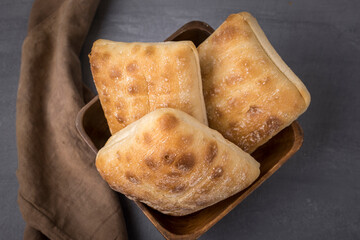 Three ciabatta bread rolls in a bowl.