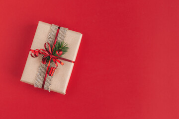 Craft gift box with spruce branch on a red background. Holiday eco-friendly concept.