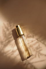 Small perfume golden bottle on warm pastel