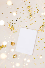 Festive gold background. Empty paper blank, shining stars confetti and fairy lights on beige and Set Sail Champagne background. Christmas. Wedding. Birthday. Flat lay, top view, copy space