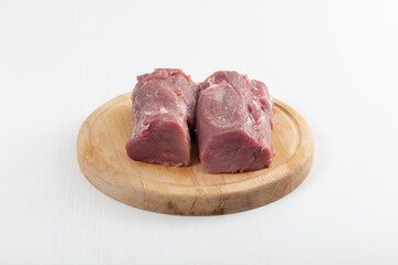 Two rolls of raw pork tenderloin on a wooden board.