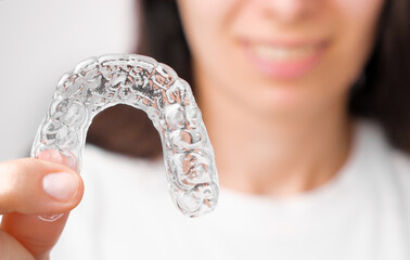 Close up orthodontic transparent aligner in womans hand. Removable braces. © vladim_ka