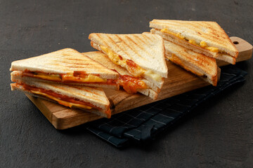 Sandwiches cut into halves on wooden cutting board with napkin