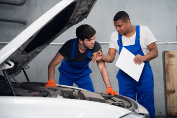 An experienced mechanic gives advice to a novice about repairing a automobile