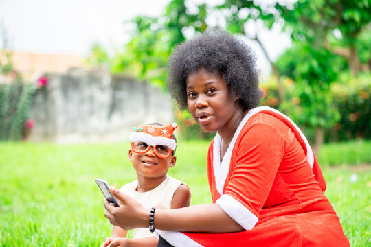image of african lady holding smart phone, a kid bit blurred.