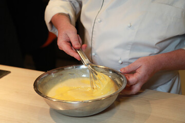 A cheft quickly whisking in egg yolk into a dough to make a cake