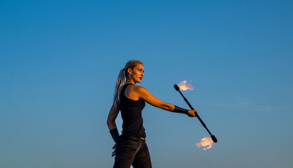 Flirting with danger. Sexy fire performer blue sky. Sensual woman manipulate flaming rod. Fire...