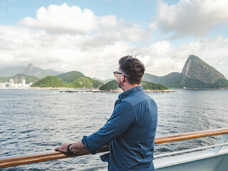 Fashionable man on the empty deck of a cruise liner against a background of sea waves. Side view,...