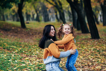mom and daughter are walking in the autumn park