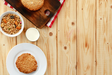 Oat cookies with oat flakes and cup of milk on wooden table