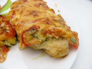 Chicken fillet baked in the oven under a cheese coat with tomatoes, sweet pepper, mayonnaise and mustard.