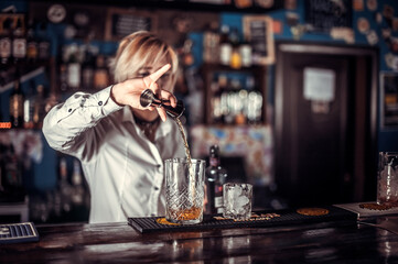Portrait of woman barman places the finishing touches on a drink at the bar counter
