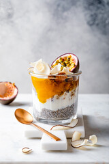 Healthy tropical fruit chia pudding with granola, mango, passion fruit and coconut chips in a glass jar. Vegan healthy breakfast, clean eating.