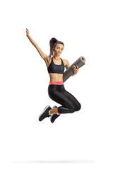 Happy young sporty female jumping and holding an exercise mat