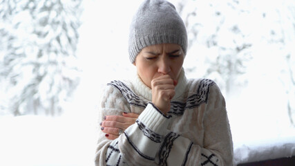 Fototapeta premium Young woman coughing outdoors in winter scenery 